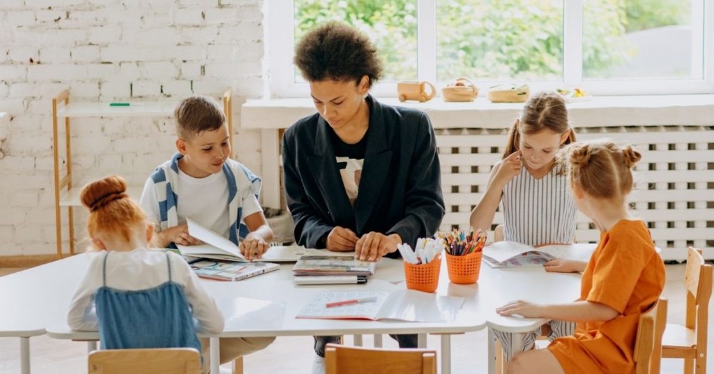 Teacher teaching a math lesson to a small group of four children at a table.