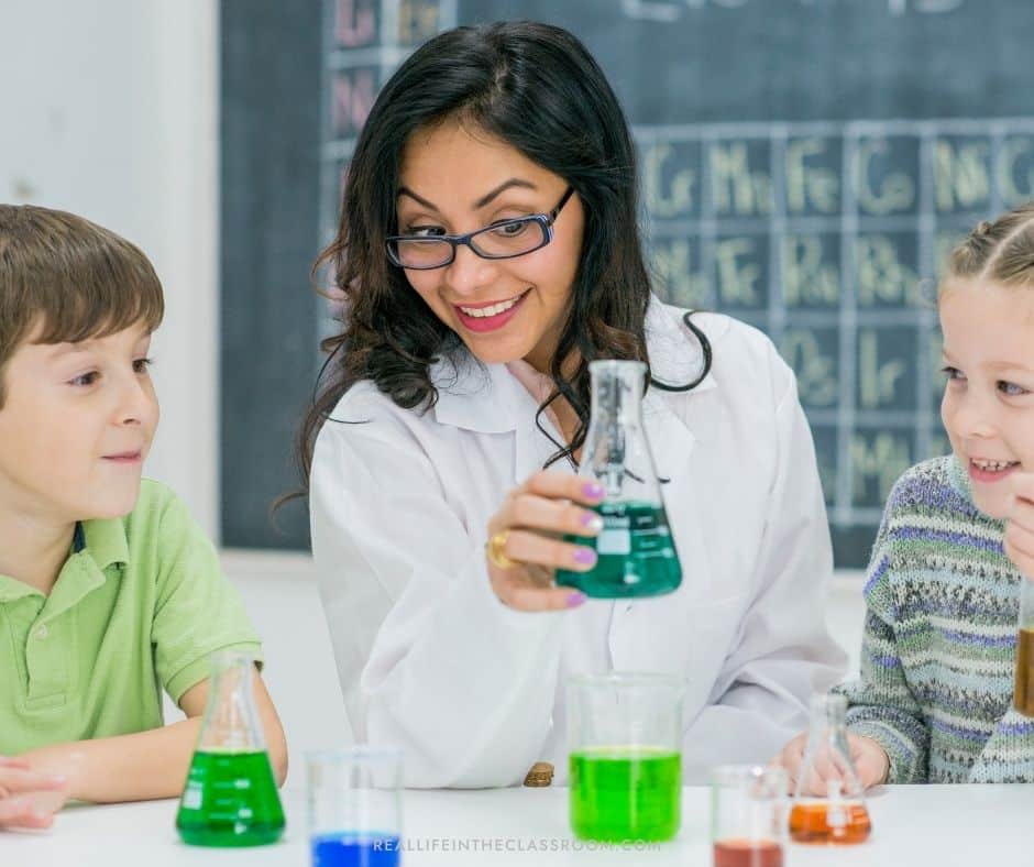 Female scientist holding a beaker with two children watching