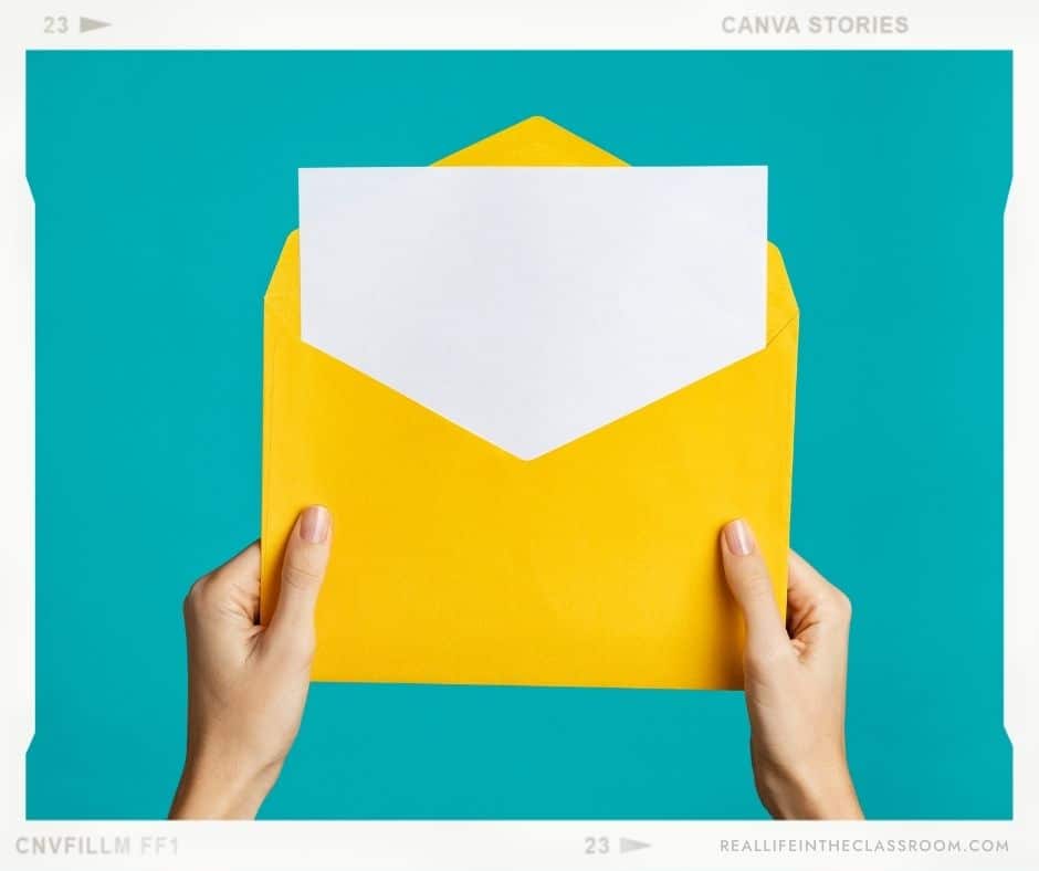 A teacher holds an envelope with a note to welcome back students to a new school year