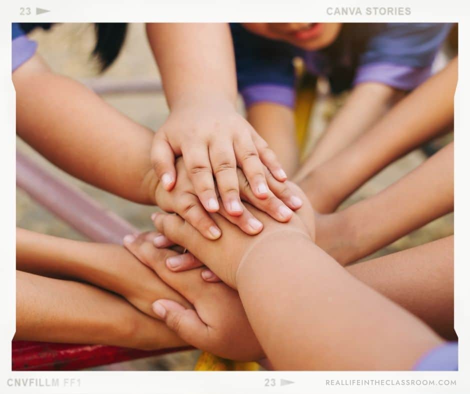Kids putting their hands together to show that they are a team.