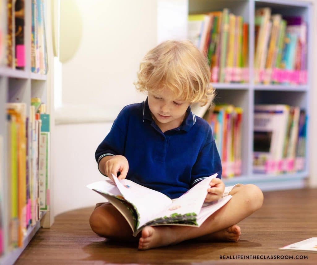 a child sitting on the floor with his legs crossed while reading a book