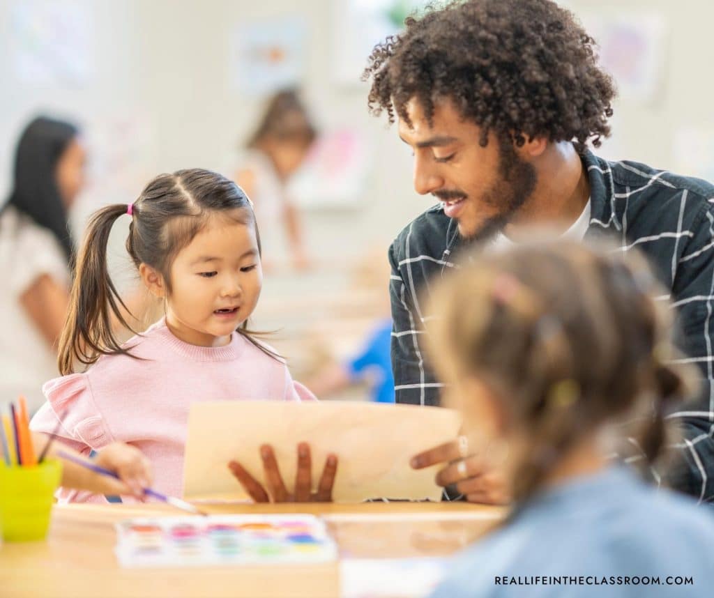 A male teacher looking at a piece of writing with a young student